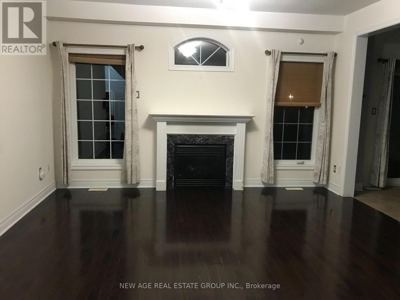A living room with a fireplace and two windows.