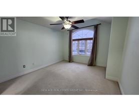A spacious room with a ceiling fan and a window with curtains.
