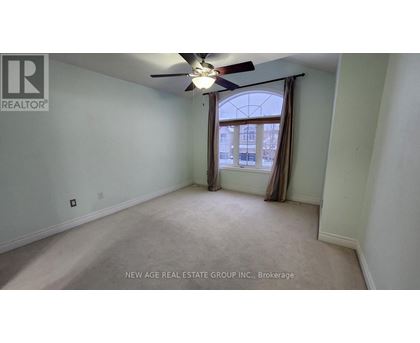 A spacious room with a ceiling fan and a window with curtains.