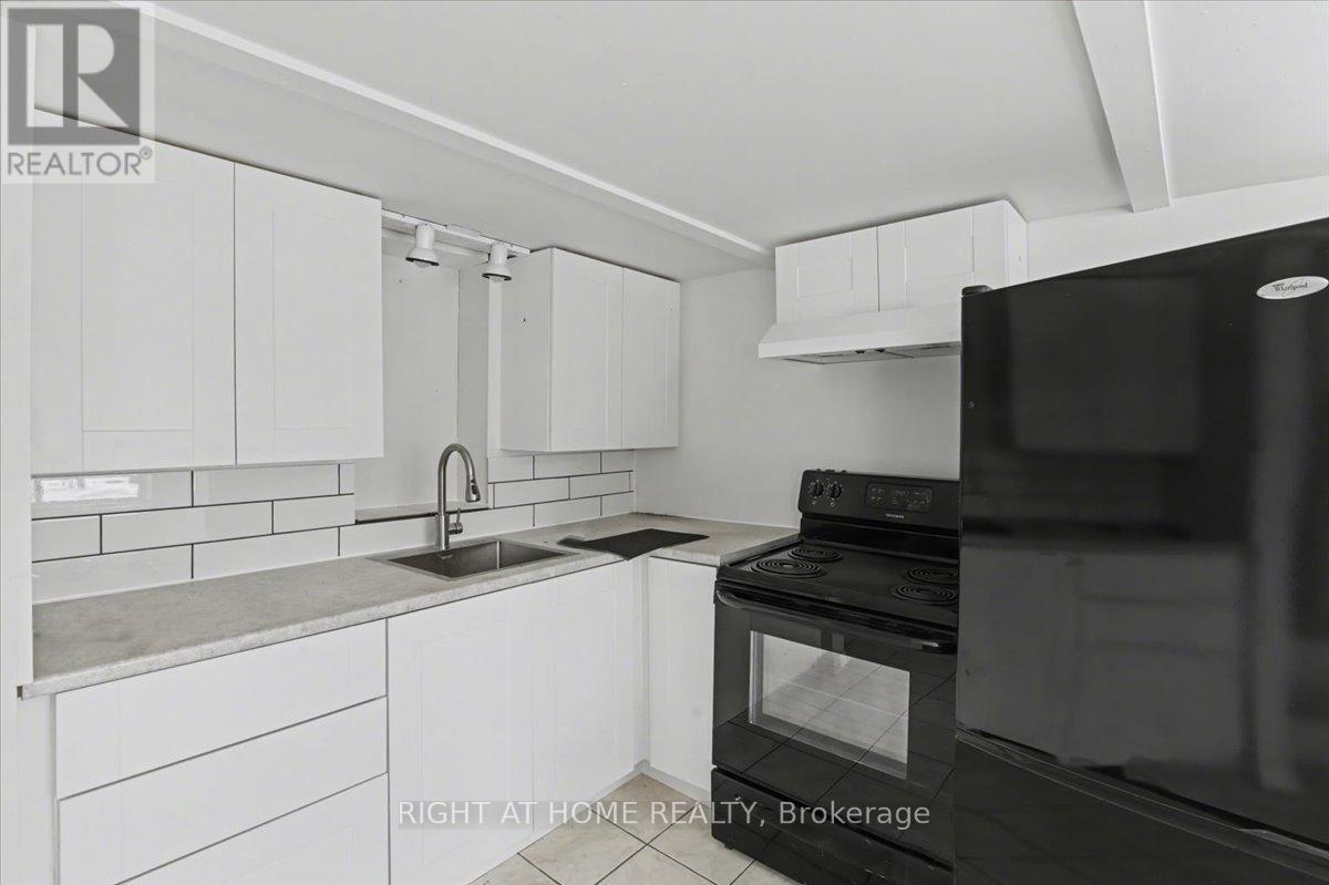 A kitchen with white cabinets and a black fridge.