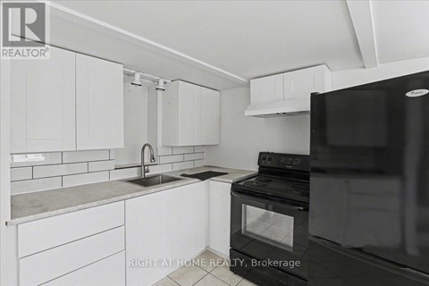 A kitchen with white cabinets and a black fridge.