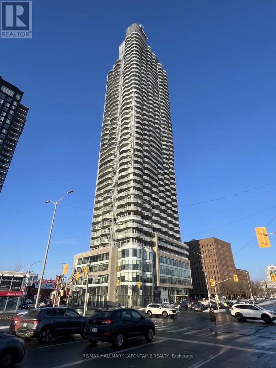 A tall building with a pattern of windows stands in the middle of a city street.