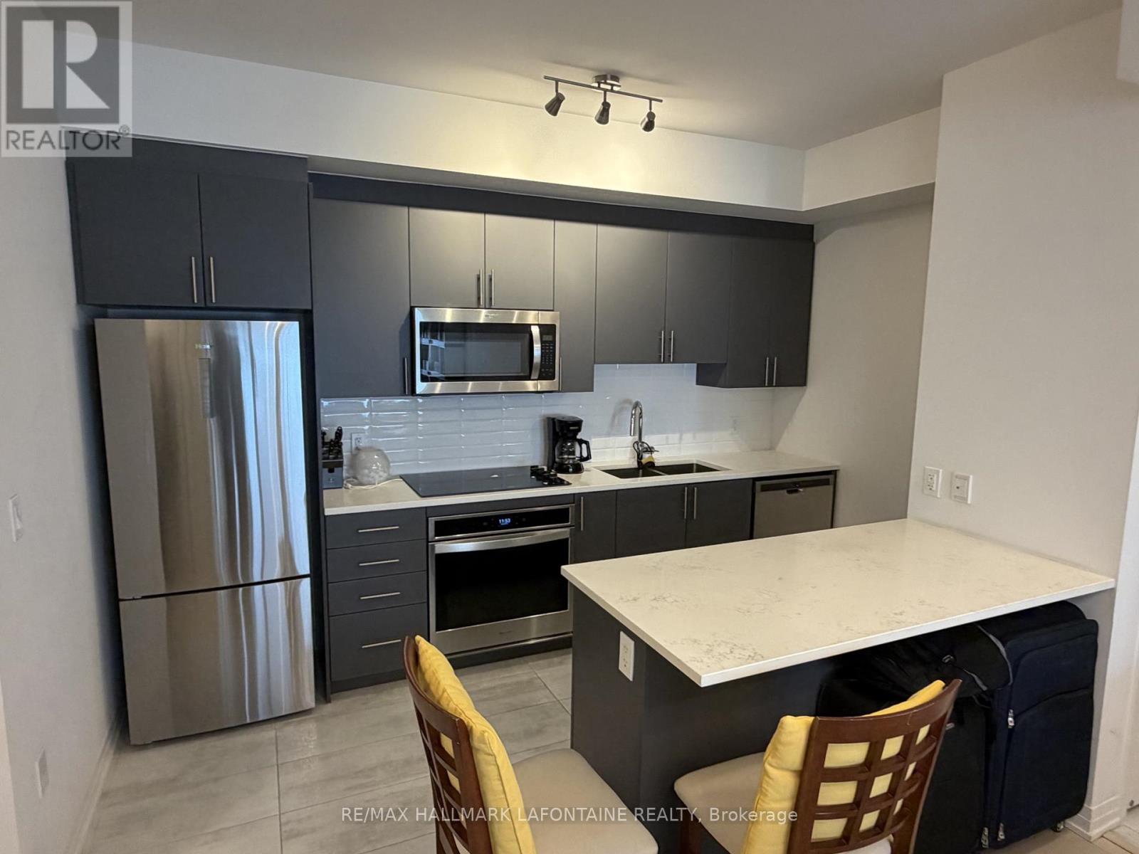 A kitchen with a refrigerator, microwave, oven, and sink.