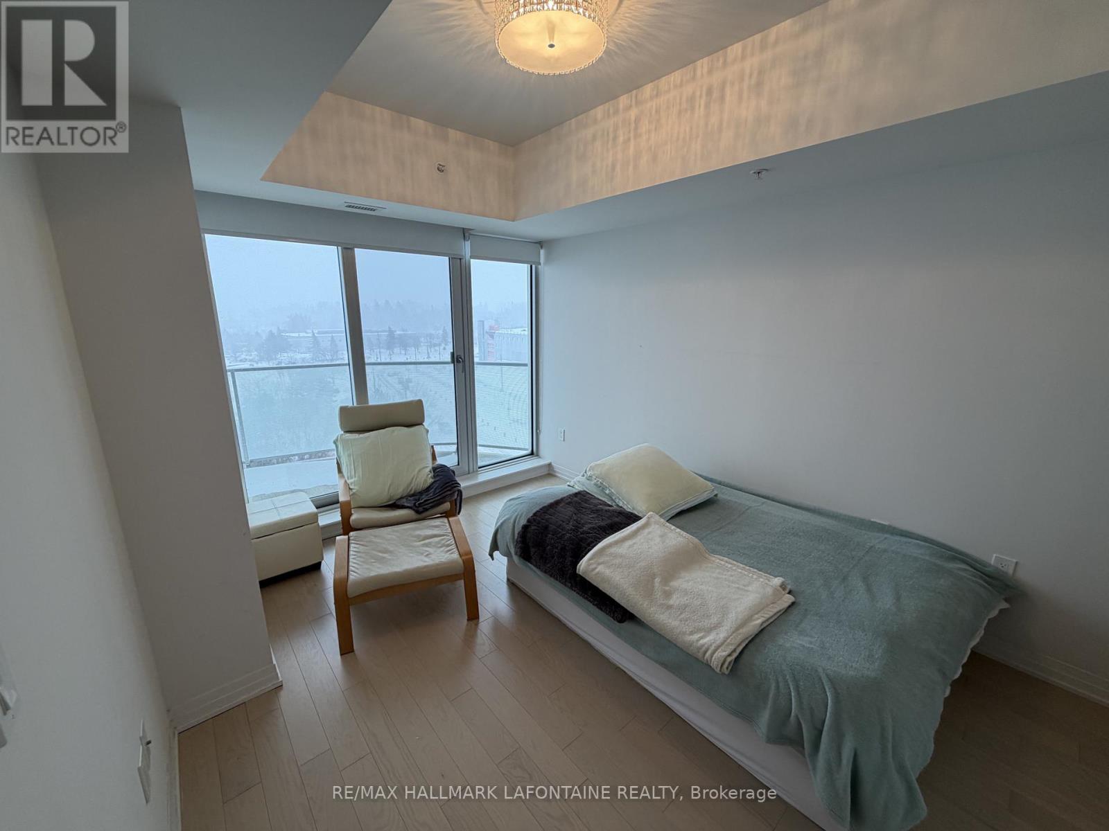 A bedroom with a bed, chair, and window.