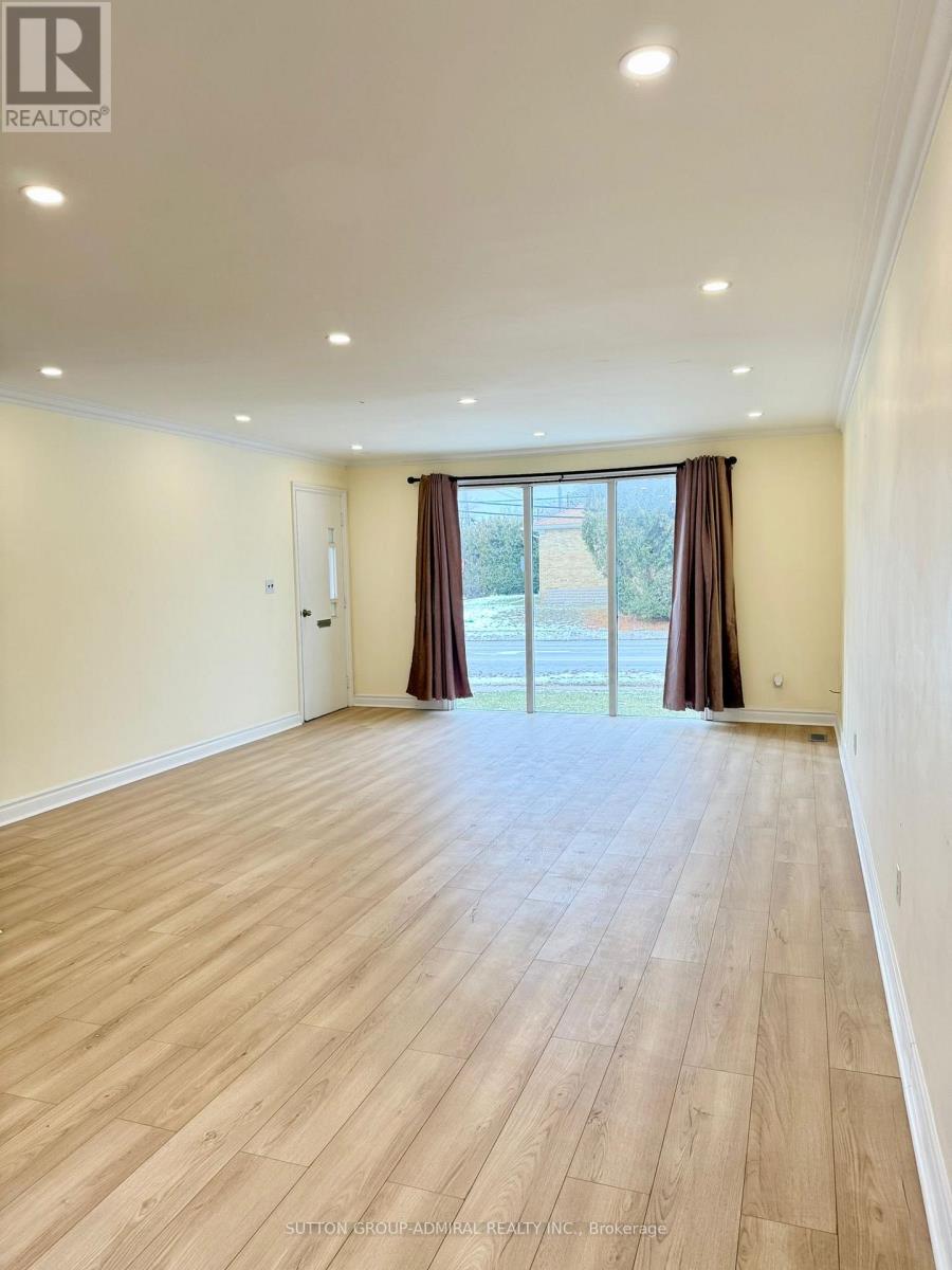 A spacious room with wooden flooring and a sliding glass door.