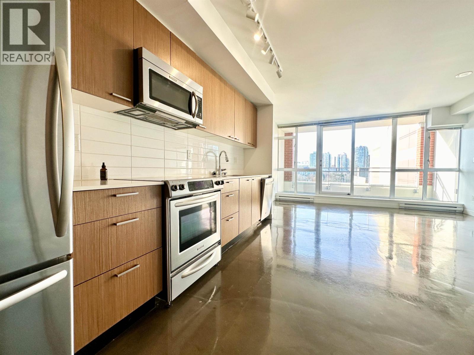 A modern kitchen with stainless steel appliances and wooden cabinets.