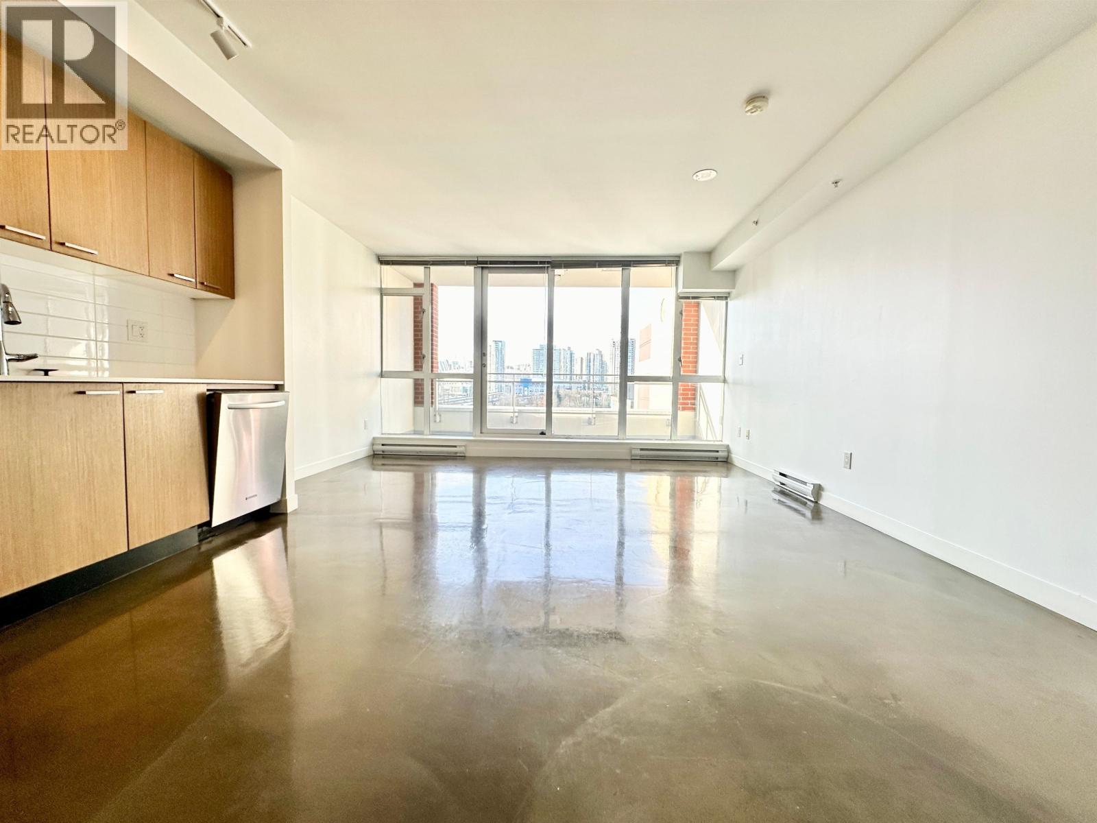 A spacious, empty room with a large window overlooking a cityscape.