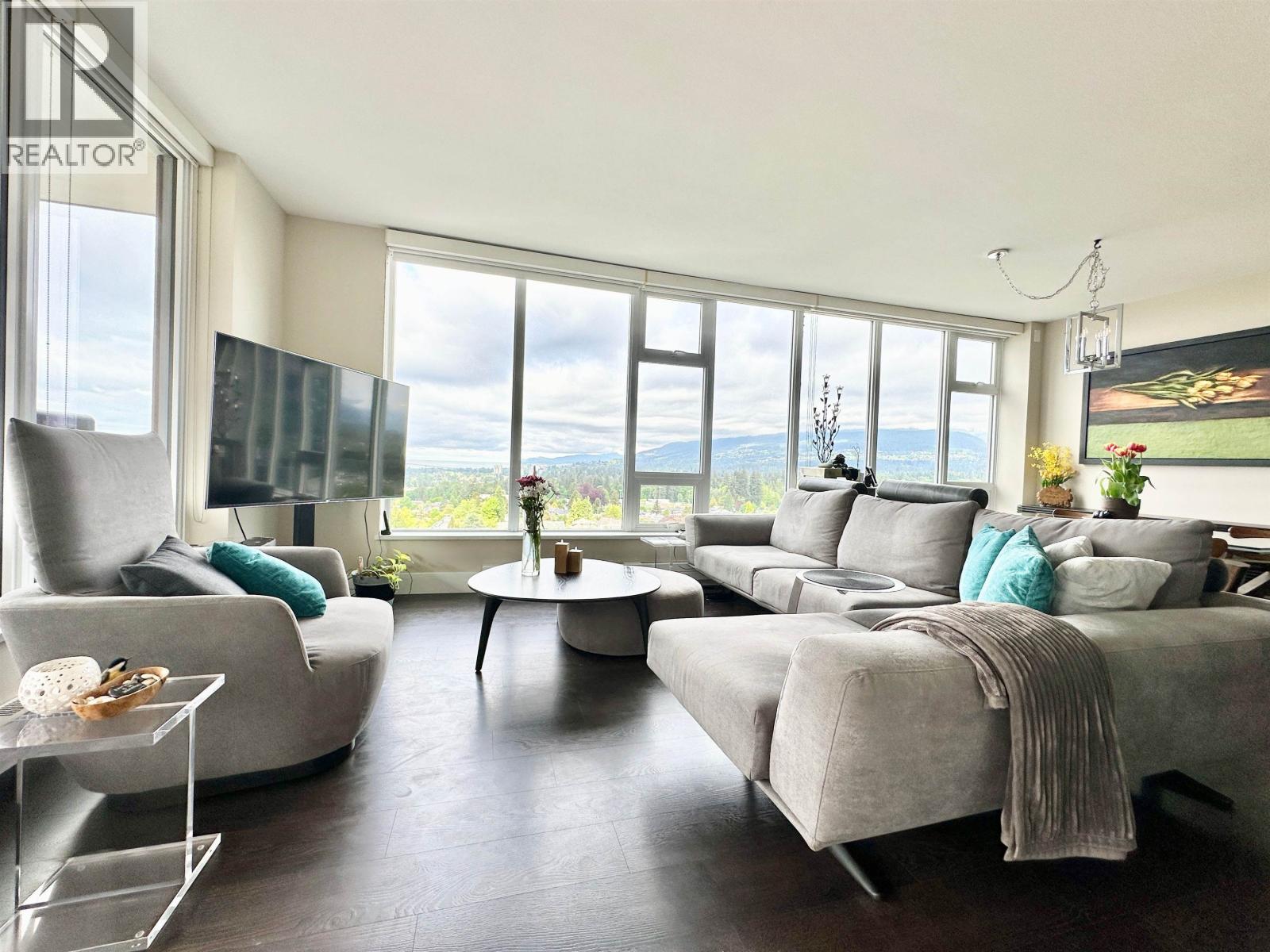 A living room with a grey couch and a glass table.