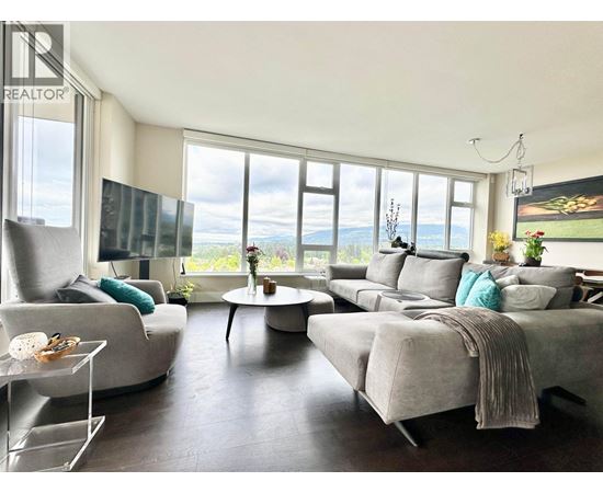 A living room with a grey couch and a glass table.