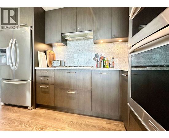 A kitchen with a refrigerator and wooden floors.