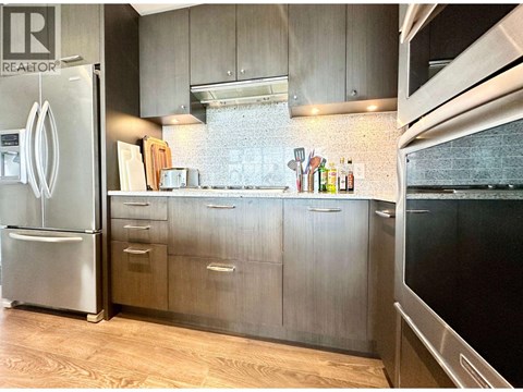 A kitchen with a refrigerator and wooden floors.