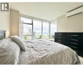 A bedroom with a large bed and a window overlooking a cityscape.