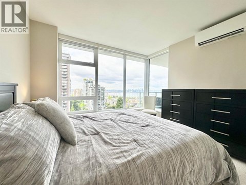 A bedroom with a large bed and a window overlooking a cityscape.
