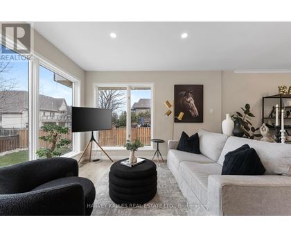 A living room with a grey couch, a black chair, and a black lamp on a tripod stand.