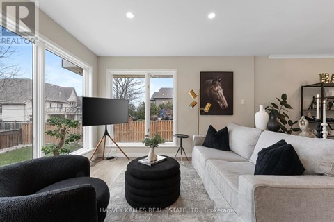 A living room with a grey couch, a black chair, and a black lamp on a tripod stand.