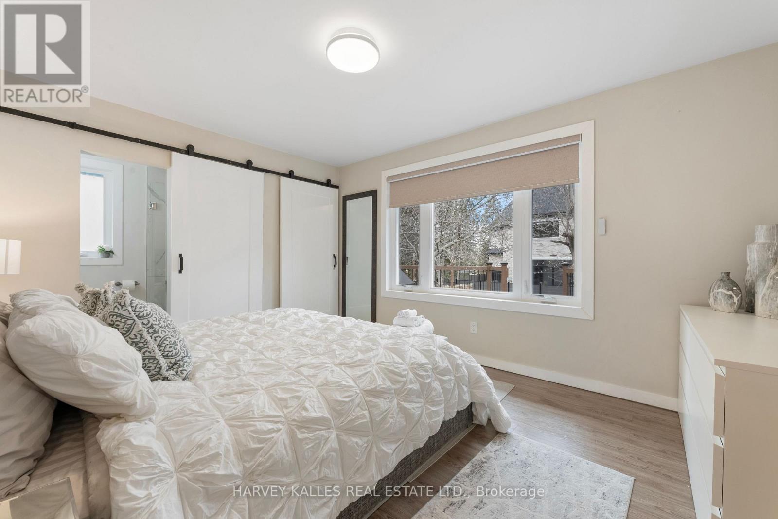 A bedroom with a bed, a window with a view of a snowy landscape, and a nightstand with a lamp.