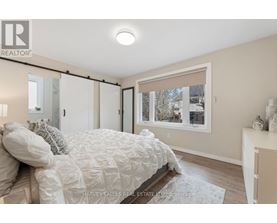 A bedroom with a bed, a window with a view of a snowy landscape, and a nightstand with a lamp.