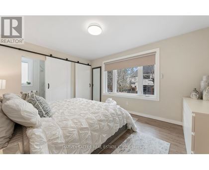 A bedroom with a bed, a window with a view of a snowy landscape, and a nightstand with a lamp.