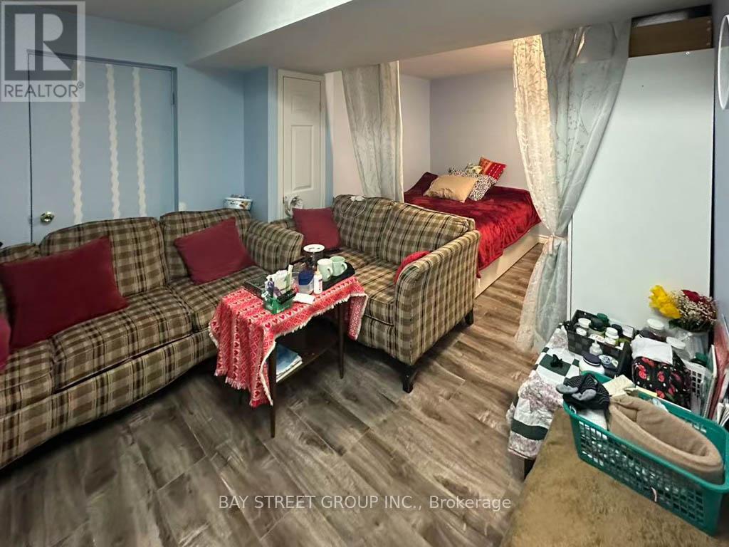 A living room with a couch, a chair, a bed, and a table with a red tablecloth.