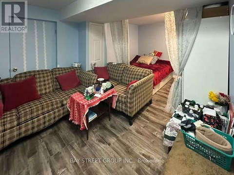 A living room with a couch, a chair, a bed, and a table with a red tablecloth.