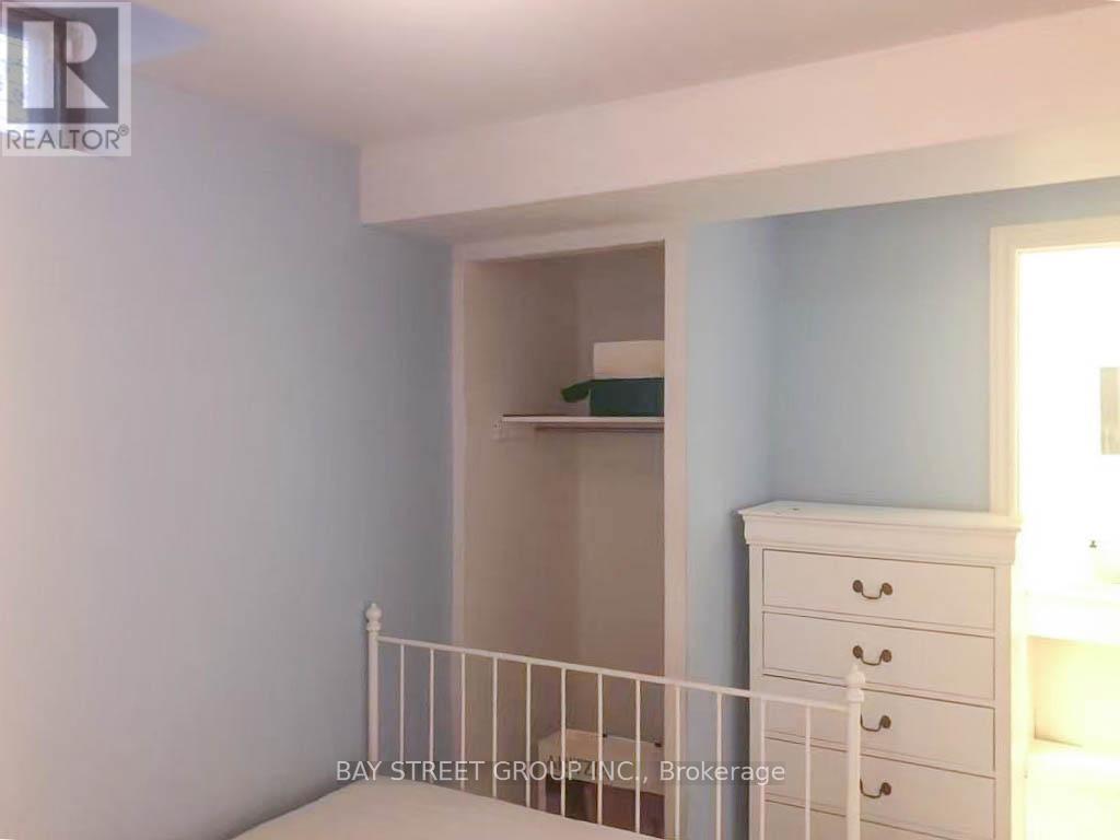A white bedroom with a bed, dresser and a window.
