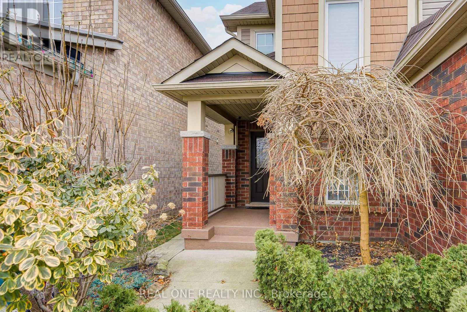 A house entrance with a brick pillar and a bush.