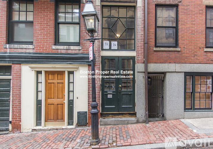 A red brick building with a black door and a sign that says Boston Proper Real Estate.