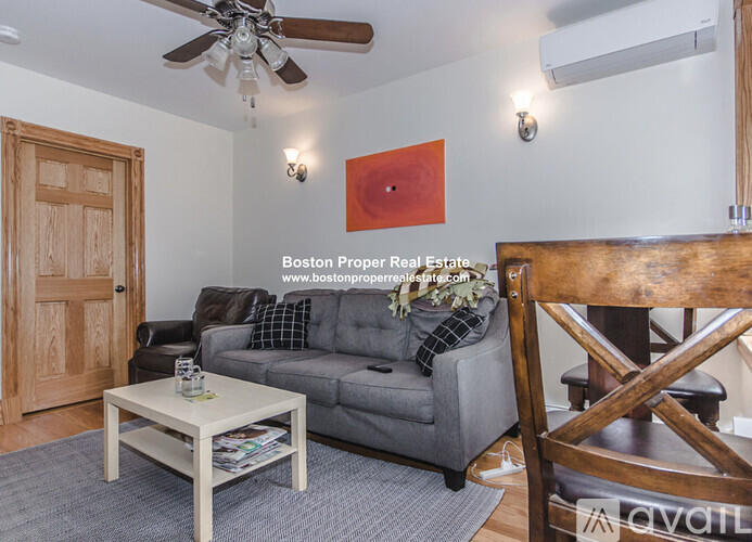 A living room with a grey couch and a wooden chair.