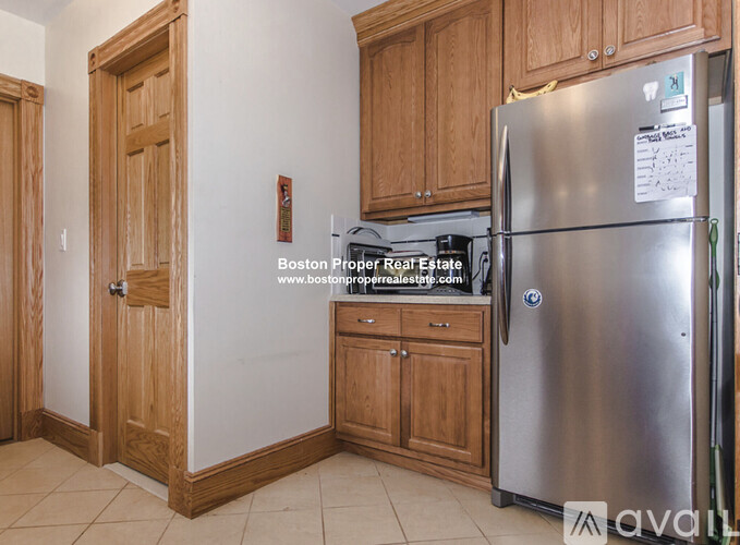 A kitchen with wooden cabinets and a stainless steel refrigerator.