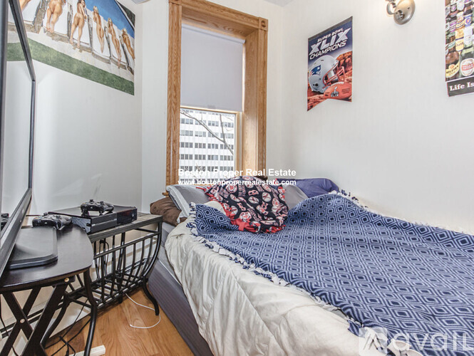 A bedroom with a bed, a chair, and a poster on the wall.
