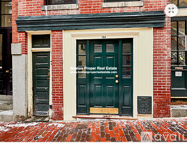 A red brick building with a green door and a sign that says Boston Proper Real Estate.