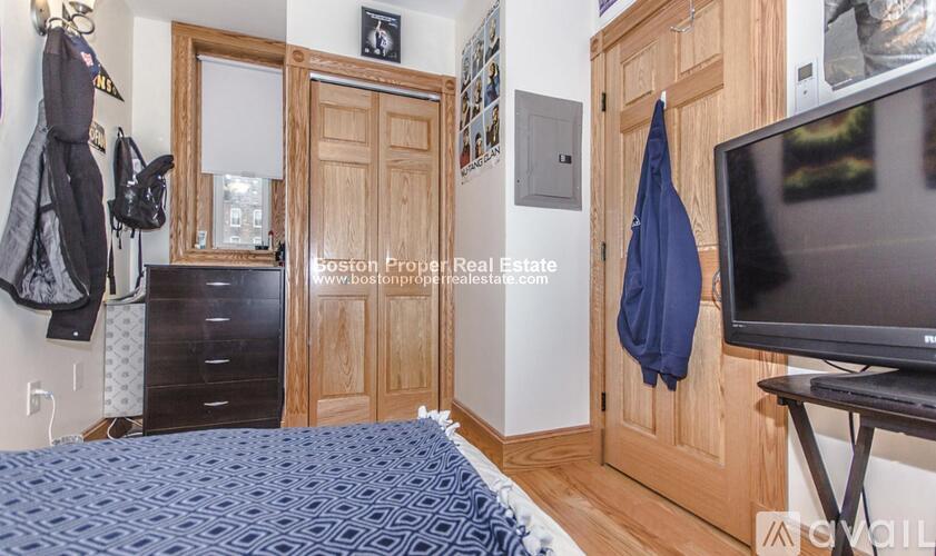 A bedroom with a bed, a dresser, a wardrobe, and a television.