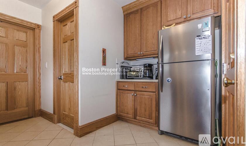 A kitchen with wooden cabinets and a stainless steel refrigerator.