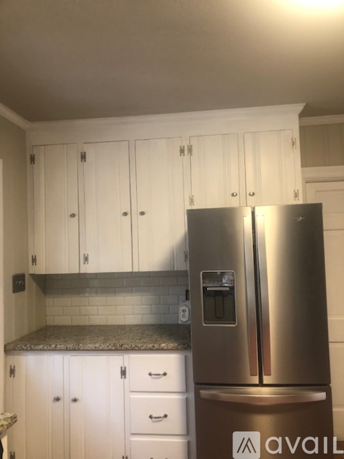 A kitchen with a stainless steel refrigerator and white cabinets.