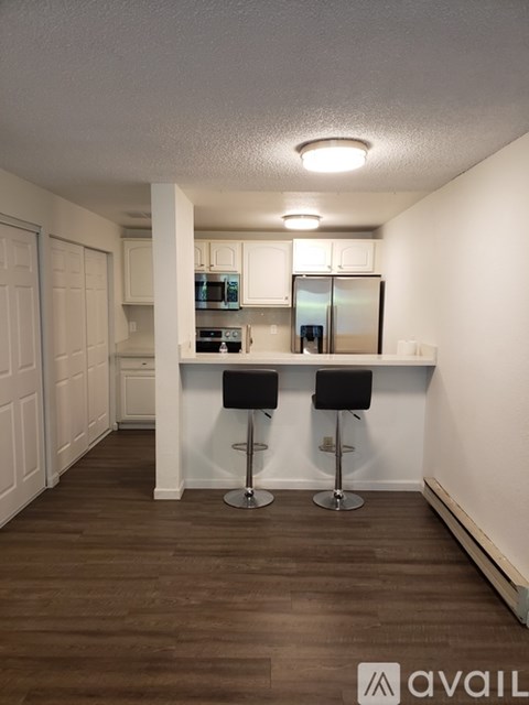 A kitchen with white cabinets and a bar with two stools.