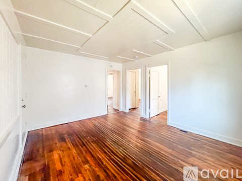 A room with wooden floors and two windows.