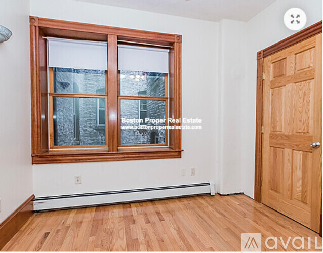 A room with a wooden floor and a window with a view of a building outside.