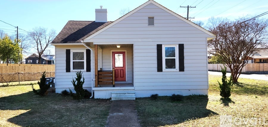 A small house with a front yard and a fence.
