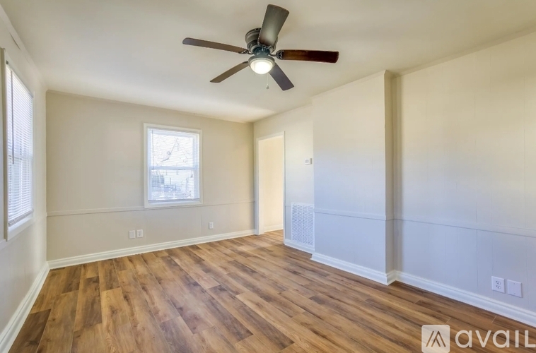 A room with a ceiling fan and wooden flooring.