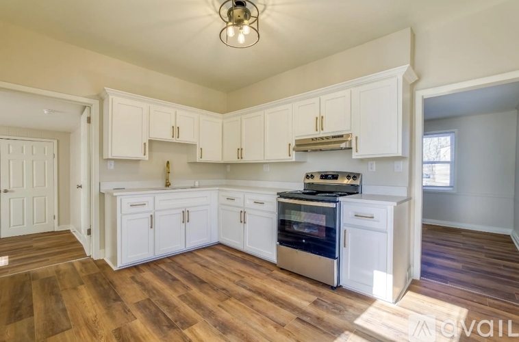 A kitchen with white cabinets and a wooden floor.