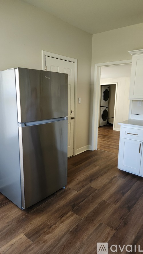 A kitchen with a stainless steel refrigerator and wooden floors.