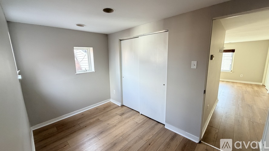 A room with a white door and a window with white blinds.