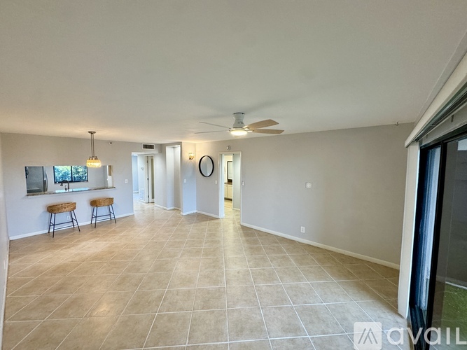 A spacious living room with a tiled floor and a ceiling fan.