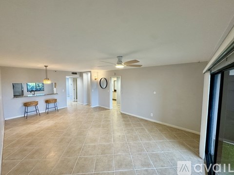 A spacious living room with a tiled floor and a ceiling fan.
