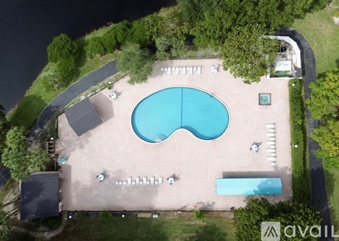An aerial view of a swimming pool surrounded by trees and a small building.
