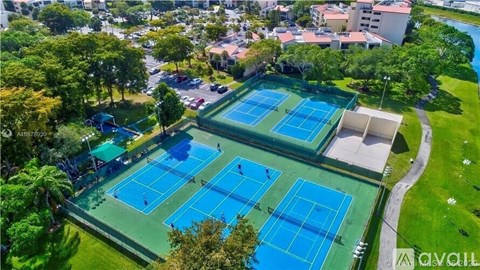 An aerial view of a tennis court surrounded by trees and buildings.