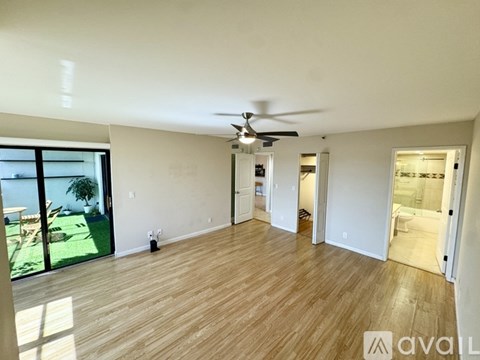 A spacious room with wooden flooring and a ceiling fan.