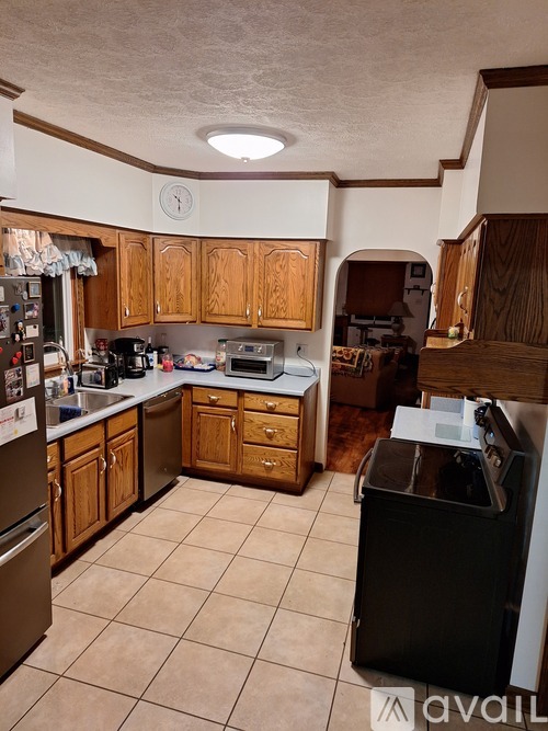 A kitchen with wooden cabinets and a black trash can.