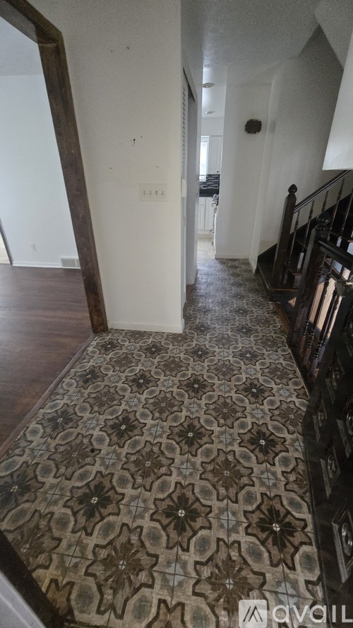 A hallway with a patterned carpet and a staircase.