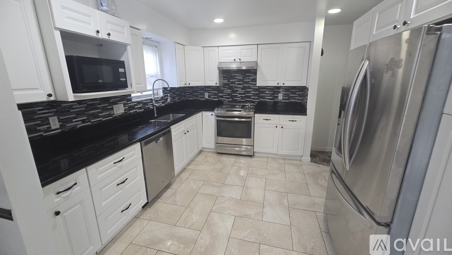 A kitchen with white cabinets and black countertops.
